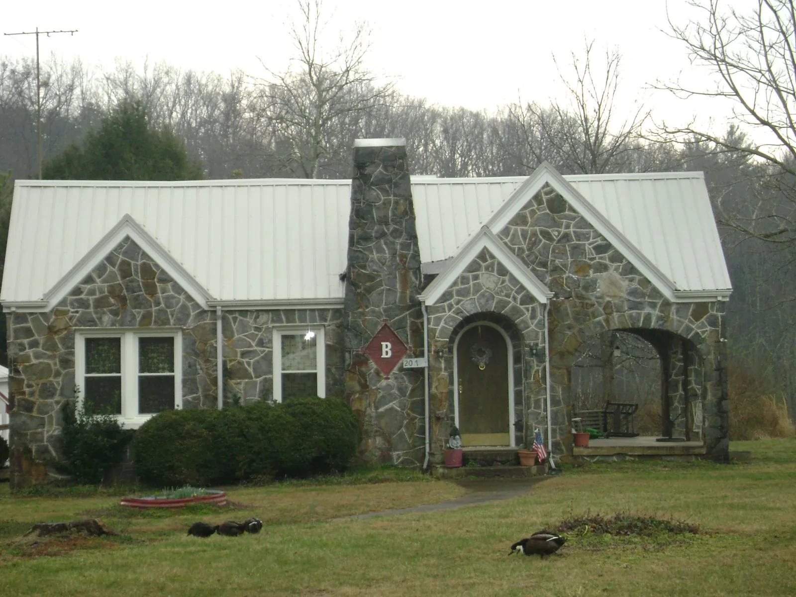 White metal roof on a stone cottage with steep gables in Wheatland