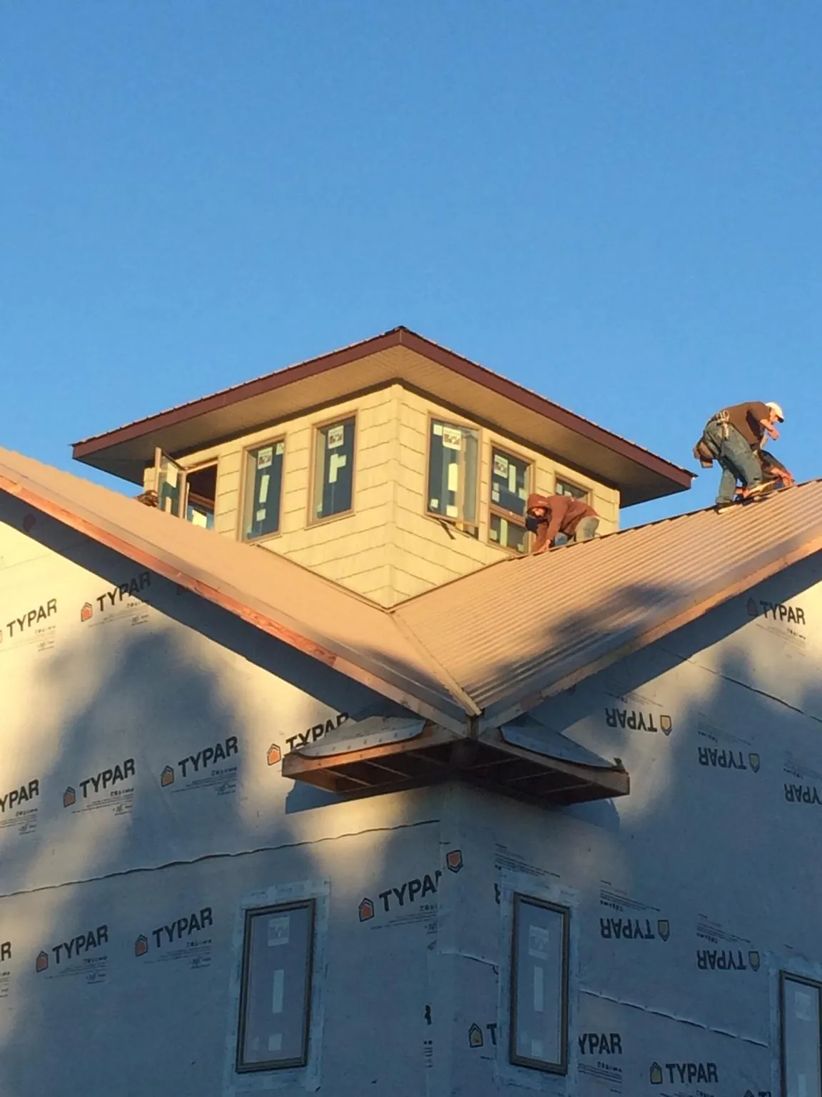 Roofers working around a rooftop cupola on a new metal roof at sunset — Roof Waterproofing in Wheatland by Roofing Brothers